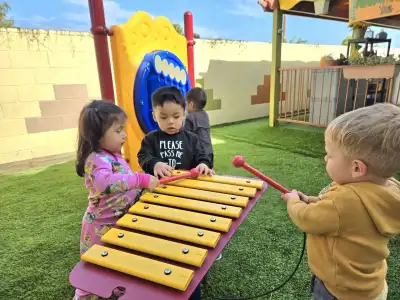 Children playing musical instruments outdoors during a music enrichment lesson at Newport Ave Preschool
